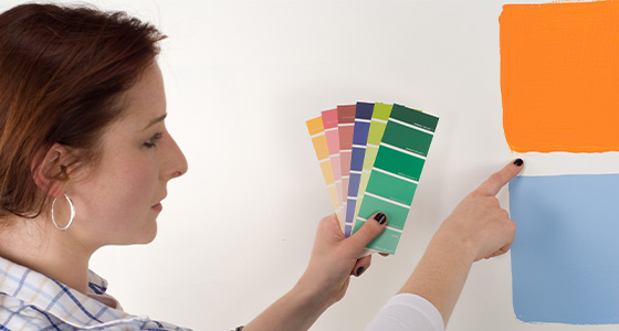 Femme qui choisi les couleurs à l'aide d'un nuancier de couleurs en vue de réaliser un mur décoratif. Section décoration